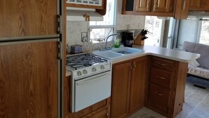 Una cocina compacta con gabinetes de madera, una estufa blanca, un microondas y un lavaplatos.