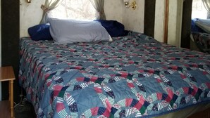 Un dormitorio con cama, armarios de madera arriba y una ventana con cortinas.