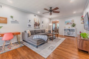 A modern living room with a grey sofa, wooden coffee table, and a ceiling fan.