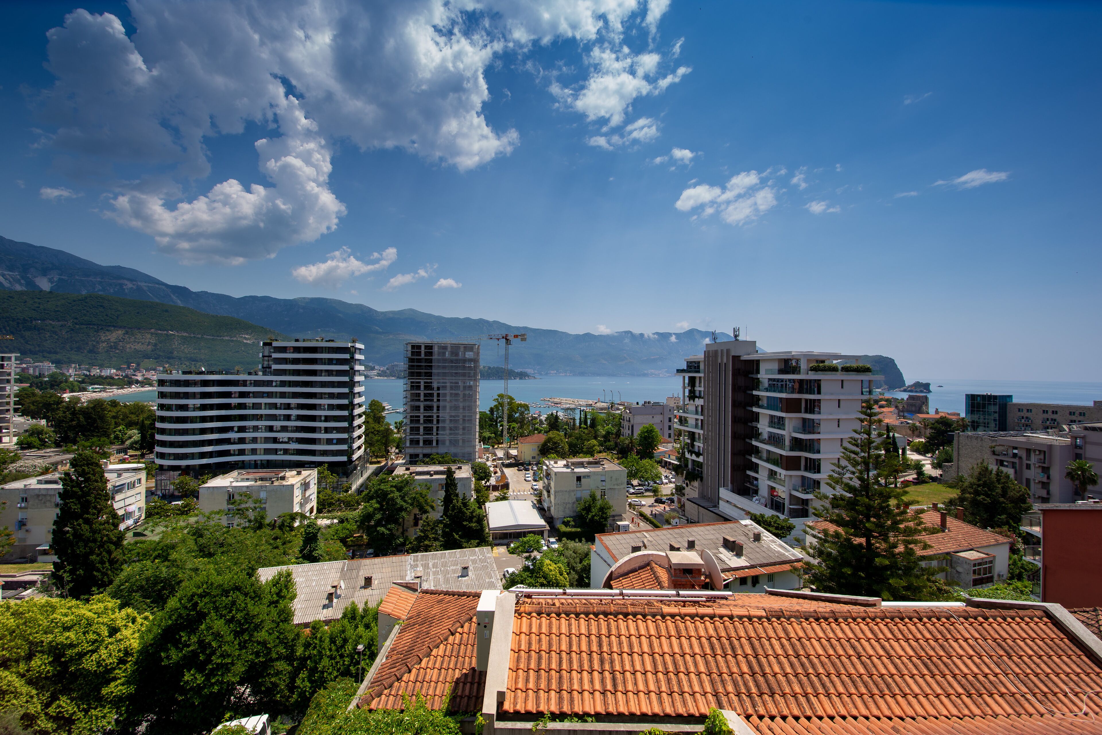 A coastal cityscape with modern and traditional buildings, a clear sky, and a view of the sea.