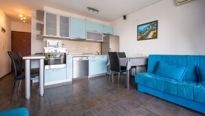 Une cuisine moderne avec des meubles de couleur bleu clair, une table à manger avec des chaises et un canapé bleu dans l’espace salon.