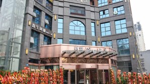 A hotel with a modern facade, multiple floors, and a prominent entrance with glass doors. - Caifu Holiday Hotel (Chongqing)