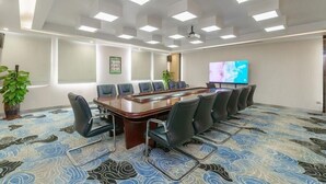 A conference room with a long table, chairs, a projector screen, and a patterned carpet. - Caifu Holiday Hotel (Chongqing)