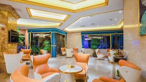 A lobby with modern seating, a chandelier, and a large window with a view. - Caifu Holiday Hotel (Chongqing)