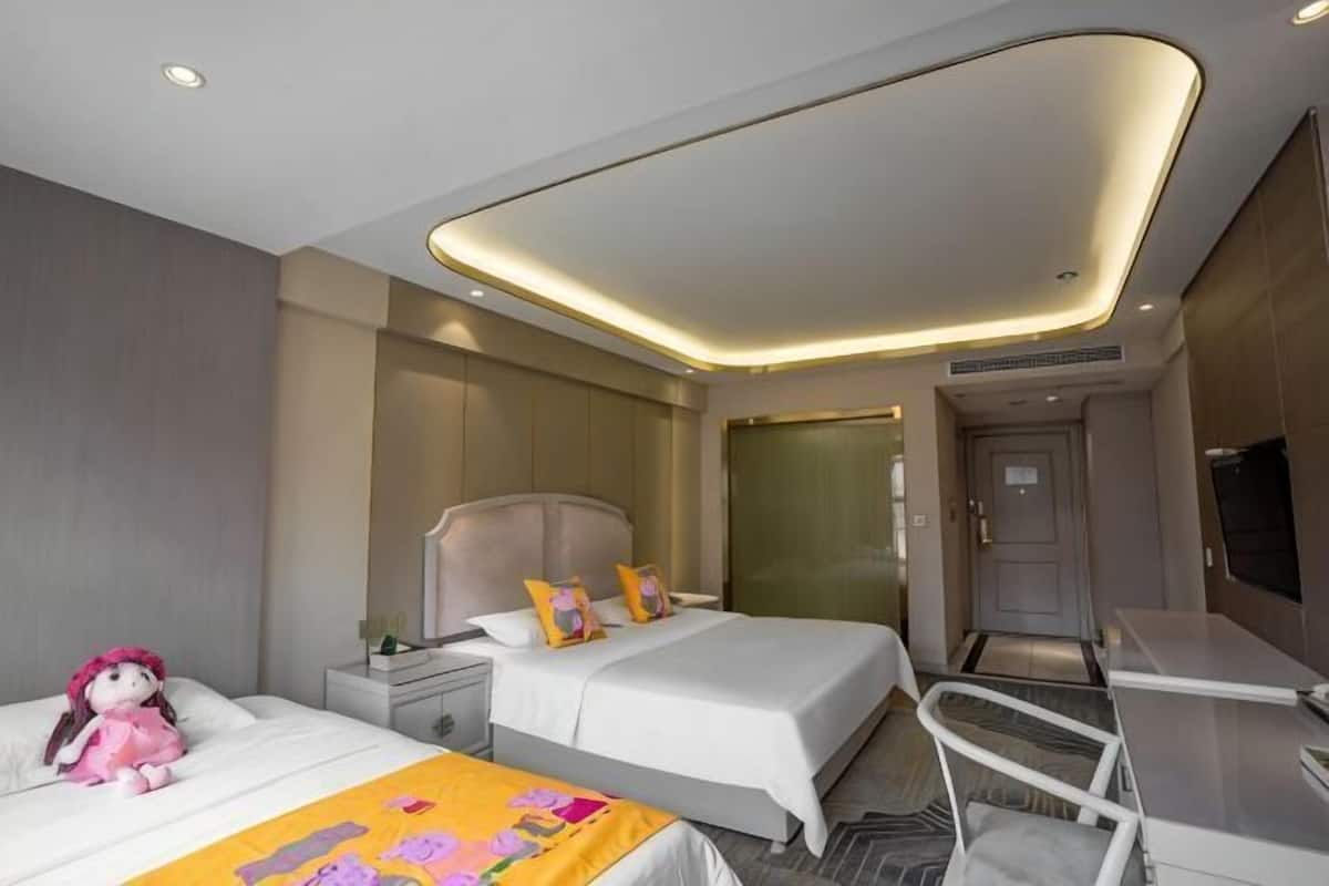 A modern hotel room with two beds, a desk, and a television.