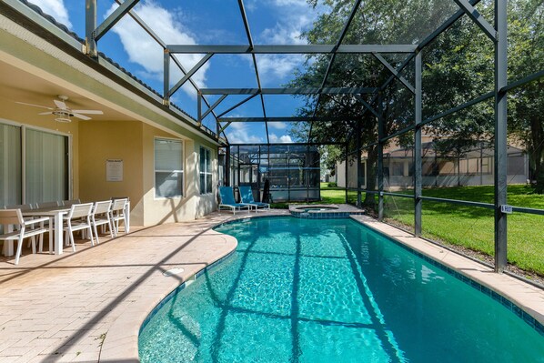 Una piscina con zona cubierta, ventilador de techo y mobiliario exterior.