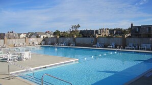 A rectangular swimming pool with a diving board and multiple lounge chairs around the perimeter. - Sound side OBX Condo no stairs, pool, enjoy the Fall, less crowds peaceful ! (Kitty Hawk)