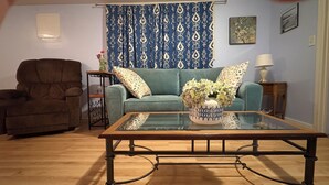 Een woonkamer met een bank, fauteuil, salontafel en decoratieve vaas.