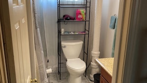 Een badkamer met een toilet, een plank met toiletartikelen en een handdoekhouder.
