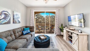 Ein Wohnzimmer mit Sofa, Hocker und TV-Möbel.