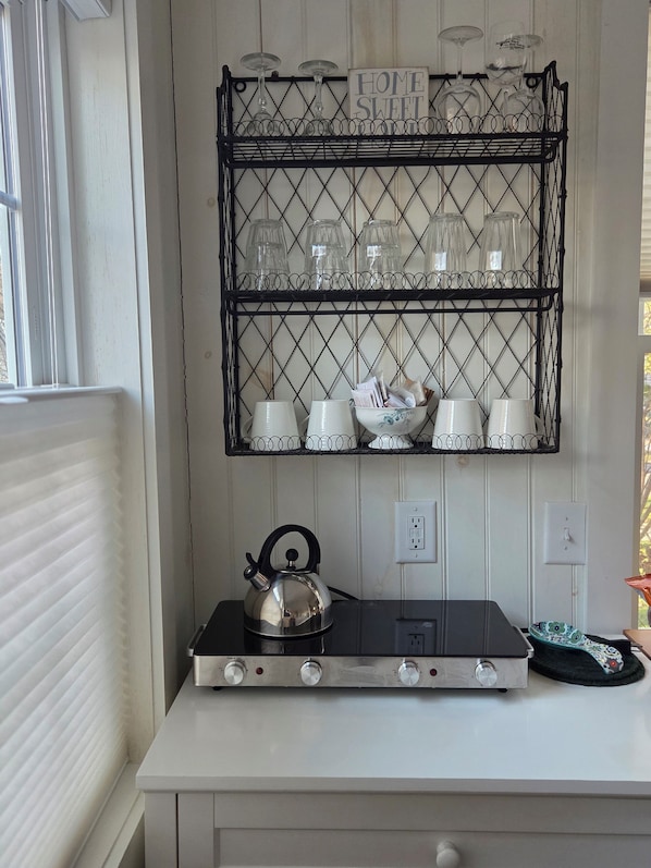 A kitchen with a gas stove, a kettle, a shelf with glassware, and a sign that reads "HOME SWEET." - Cozy So End Suite (Burlington)