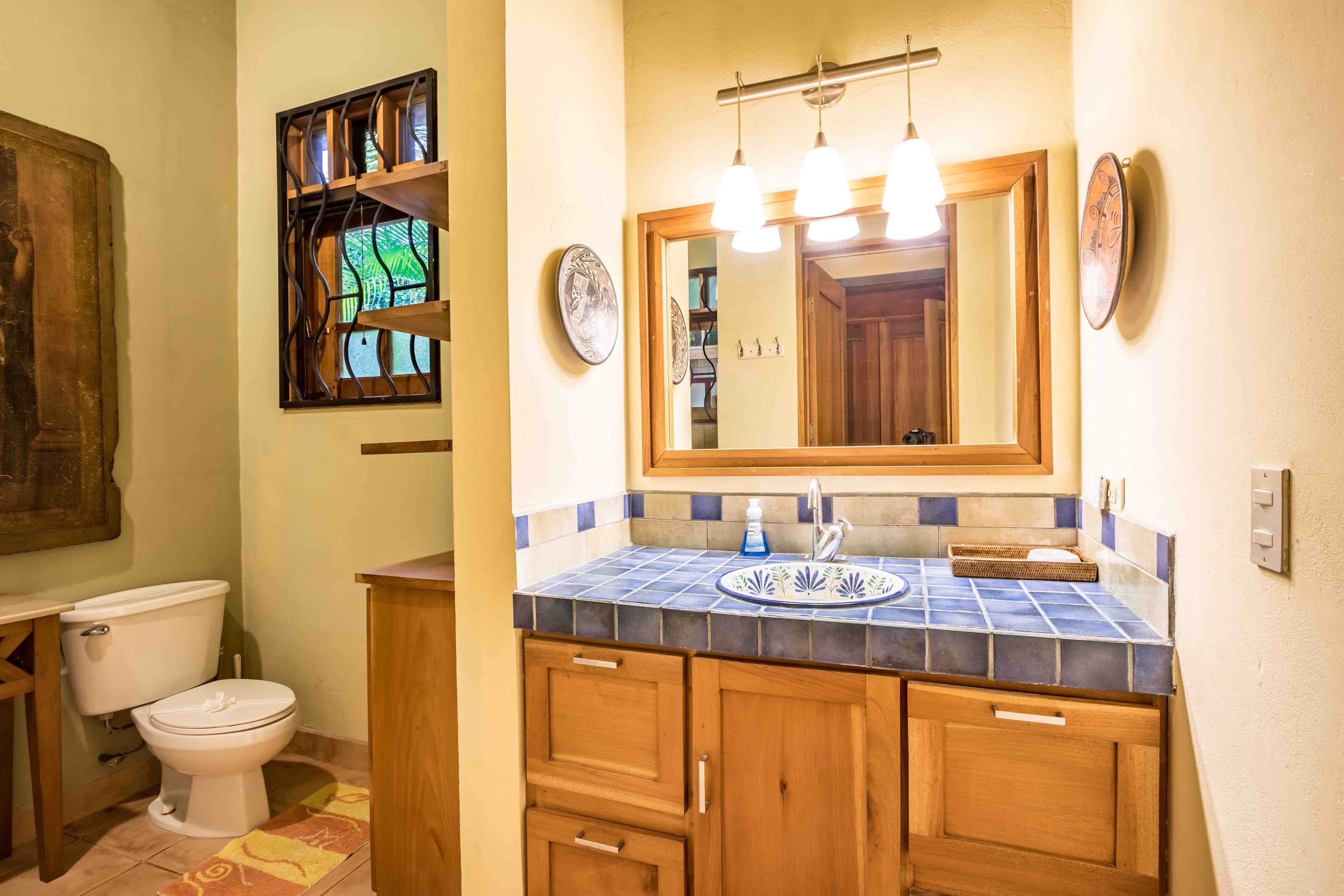 A bathroom with a toilet, sink, and mirror.