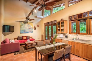 A spacious living area with a sofa, a dining table, and a ceiling fan.