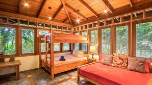 A wooden cabin with a bunk bed, a sofa, and a small table. - Sonidos Del Mar - Tropical Garden Villa (Jaco)
