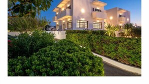 A modern two-story building with large windows and a well-maintained garden in front. - Anemos Inn Adults Only By Estia (Hersonissos)