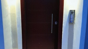 Entrada de un hotel con una puerta de madera oscura, un teclado de cierre y un cartel iluminado en la pared.