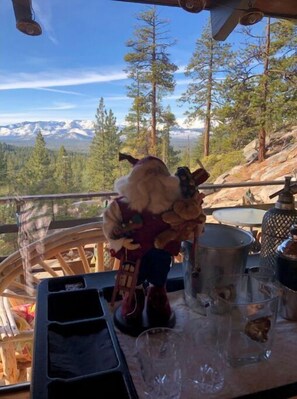 A table with a view of a mountainous landscape, a wooden chair, and a table setting including a mug and a glass.