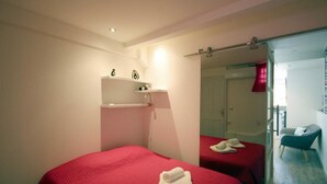 A hotel room with two beds, each with a red bedspread and white towels. There is a small shelf with decorative items above the beds. - T2 Design for 2 with small private pool, ideal for a loving couple. (Les Trois ILets)
