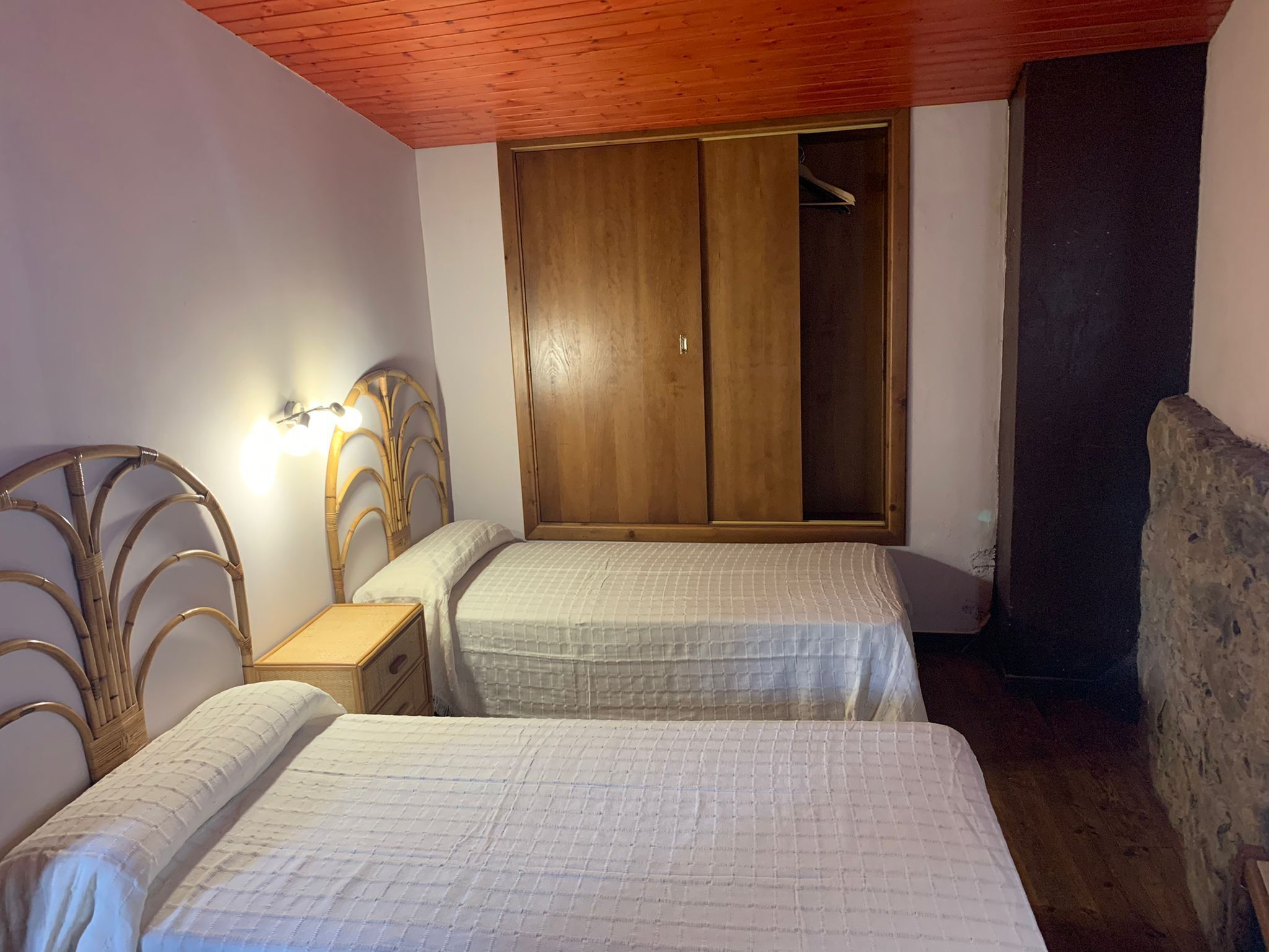 Un dormitorio con dos camas, un armario de madera y una mesita de noche.