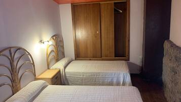 Un dormitorio con dos camas, un armario de madera y una mesita de noche.
