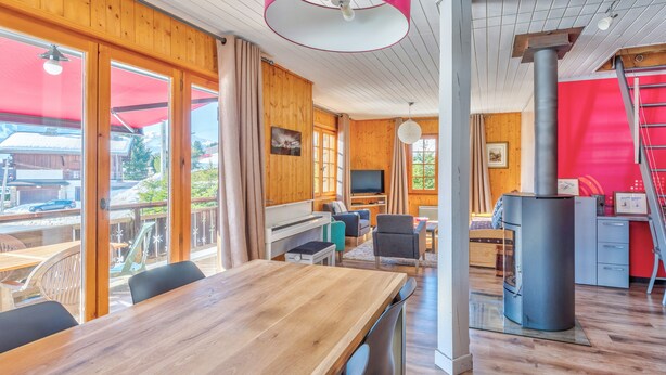 A wooden interior with a dining area, a television, and a fireplace. - Le Chalet des Neiges - Welkeys (Megève)