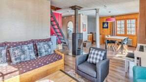 A cozy living room with a sofa, armchair, and a fireplace. - Le Chalet des Neiges - Welkeys (Megève)