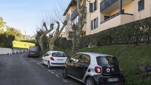 Eine Straße mit parkenden Autos und einem Gebäude mit Balkonen.