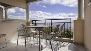 En balkon med et bord og stole, havudsigt og en klar himmel.