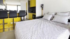 Et moderne hotelværelse med seng, et lille tekøkken og et spiseområde.