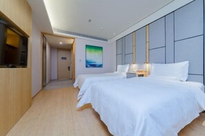 A hotel room with two beds, a TV, and a painting on the wall. - Ji Hotel (Shenzhen)