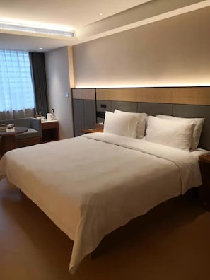 A hotel room with a large bed, bedside tables, a desk, and a window with curtains. - Ji Hotel (Shenzhen)