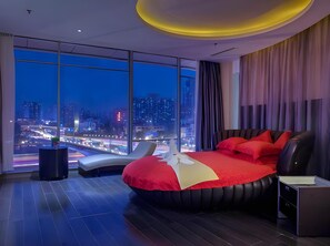 A modern hotel room with a large bed, a seating area, and a city view. - Guangdong Nanmei Osotto Hotel (Guangzhou)