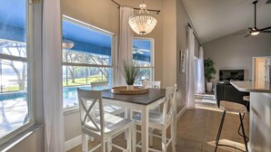 Una cocina moderna con comedor, ventanas amplias y vista a una piscina.