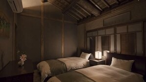 Ein Zimmer mit zwei Betten, einem Nachttisch mit Lampe, einer Kommode und einem Bild an der Wand.