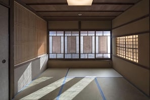Una habitación japonesa tradicional con suelo de tatami, paneles shoji y vistas a través de las ventanas.
