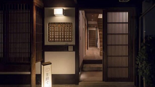 Ein traditionelles japanisches Interieur mit Schiebetüren, Holzboden und einer wandmontierten Leuchte.