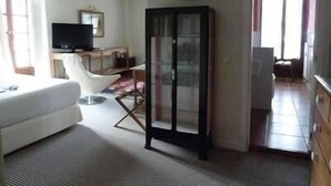 A living room with a white sofa, a television, a cabinet, and a door leading to another room. - Churrut Hotel (Vera de Bidasoa)