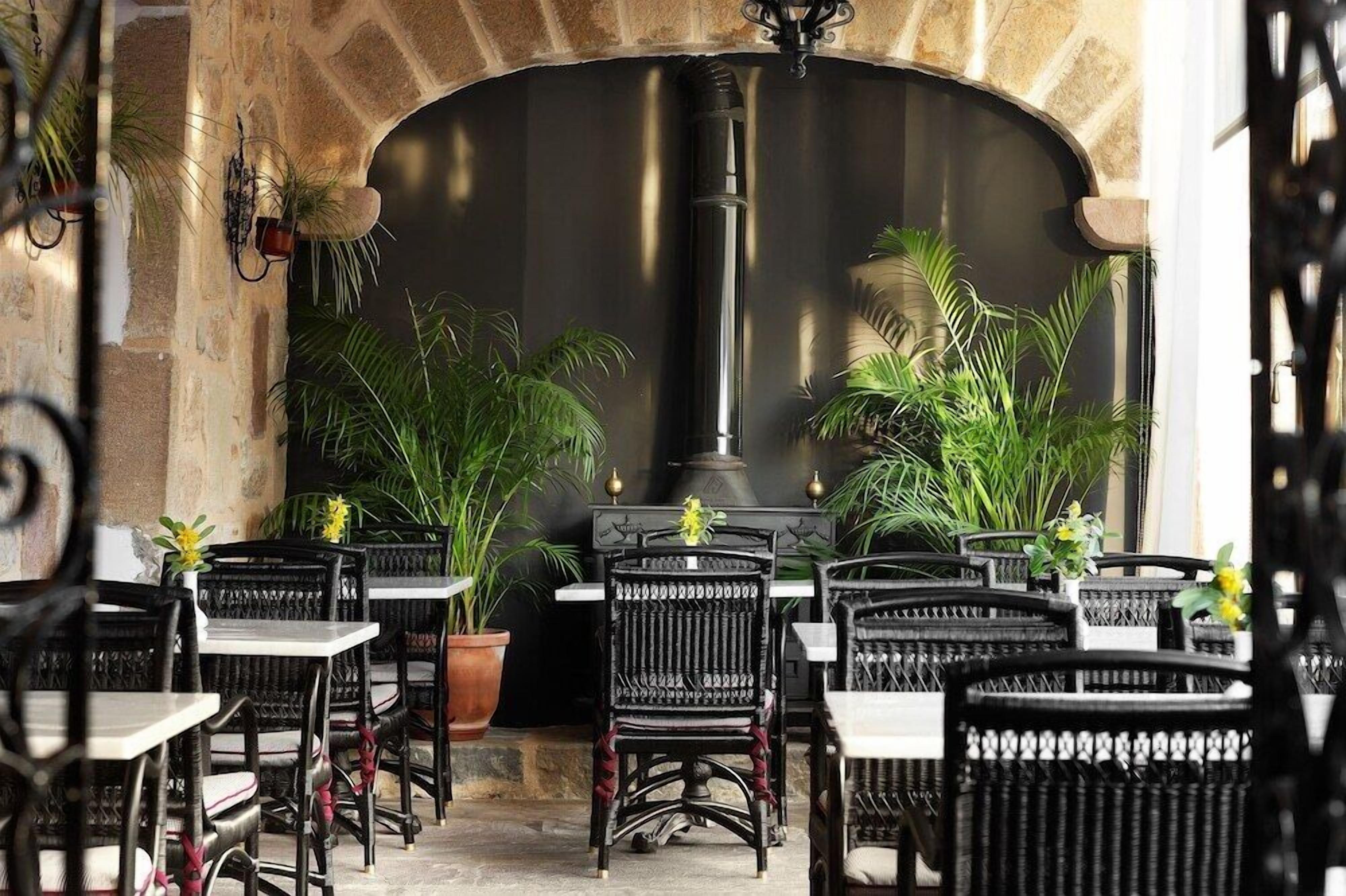 An outdoor seating area with stone walls, black wicker chairs, and potted plants.