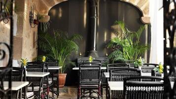 An outdoor seating area with stone walls, black wicker chairs, and potted plants.