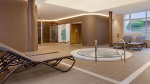 A modern indoor pool area with lounge chairs, a hot tub, and a clear view of the outdoors. - Family 2-Bed Apartment | Costa del Sol | Sleeps 6 (Las Lagunas de Mijas)
