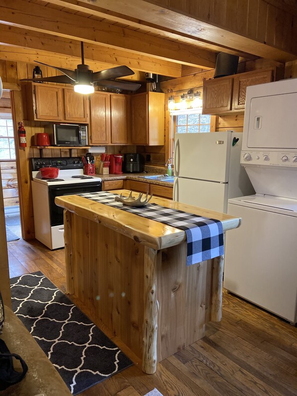 Una cocina con armarios de madera, microondas, estufa, refrigerador y un mantel a cuadros en la encimera.