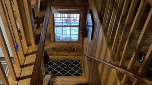A wooden staircase with a metal handrail, a window at the top, and a metal grate at the bottom. - Private creek cabin with hot tub nestled in the foothills of Cheat mountain  (Huttonsville)