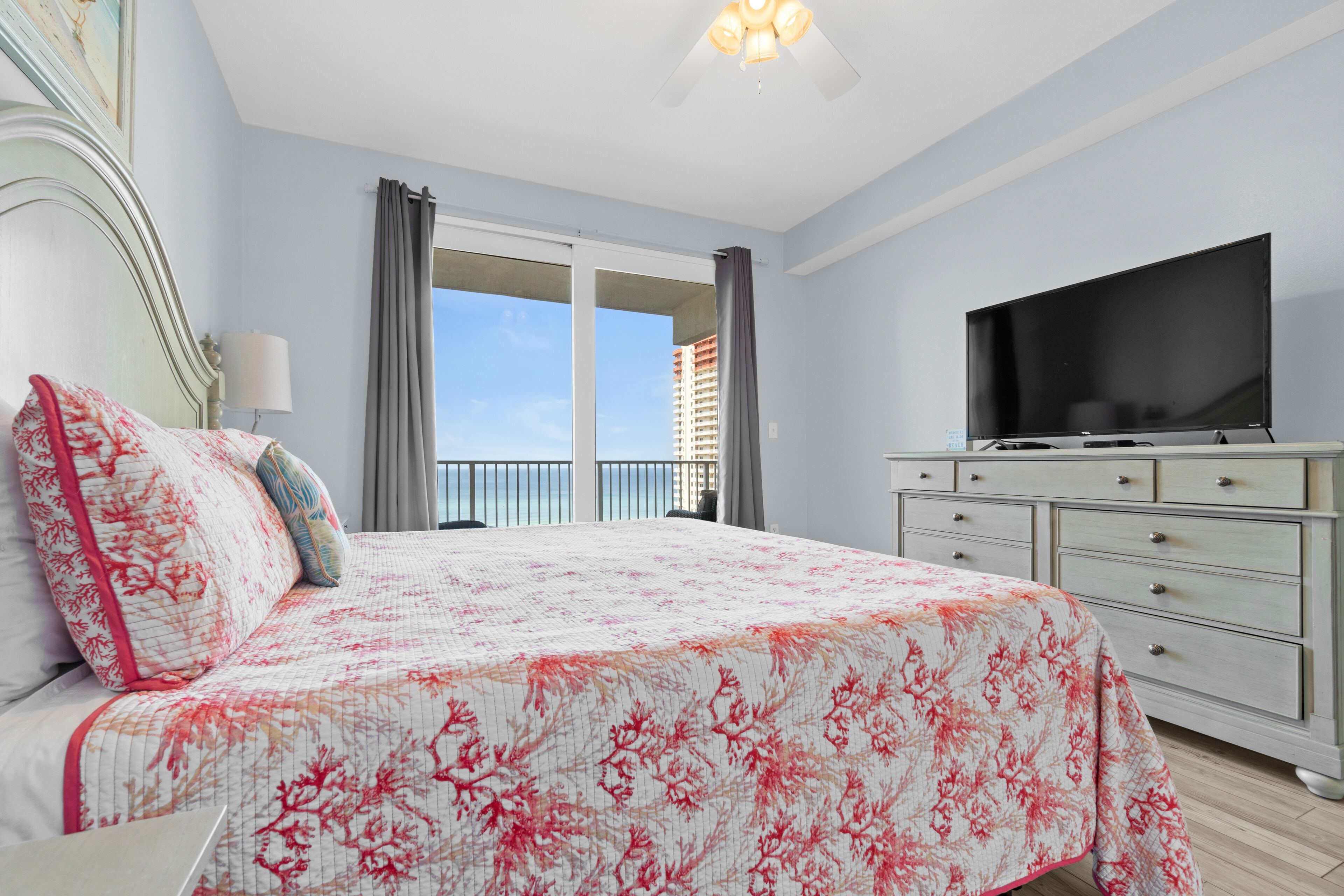 Une chambre à coucher avec un lit, une télévision, une commode et un balcon offrant une vue.