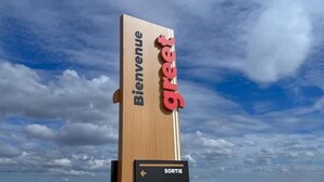A wooden sign with 'Bienvenue' and 'greet' text, and a directional sign below it.