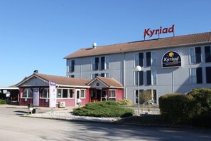 A hotel with a red sign 'Kyniad' and a sign for a restaurant.
