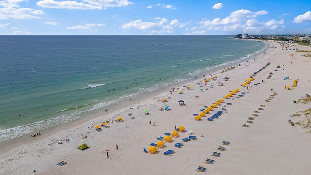 A beach with rows of sunbeds and umbrellas, a clear sky, and the ocean. - CLUB BAHIA WATERFRONT - COUNTRY CLUB USAGE (st . petersburg)