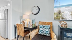 A modern kitchen with a refrigerator, a dining table with chairs, a clock, and a view of the beach. - Southbay by the Gul 69 Updated Poolside Unit 75 Yards from Beach (Destin)