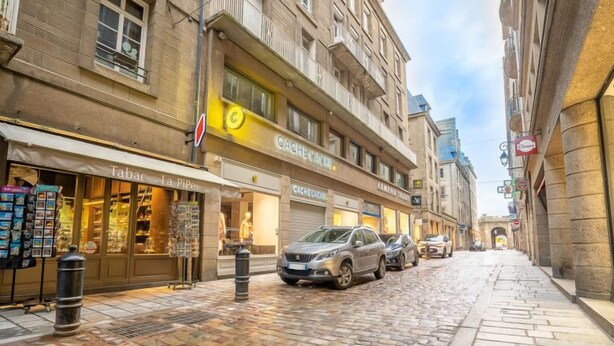 En kullerstensgata kantad av historiska byggnader, med en tobaksaffär och ett café.