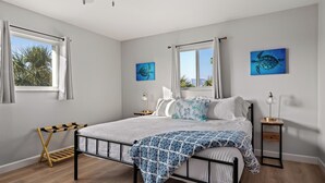 A bedroom with a bed, bedside tables, a window with curtains, and two wall-mounted paintings. - 50 steps to uncrowded beach - 2 king beds - Pac Man arcade - summer beach fun! (Englewood)
