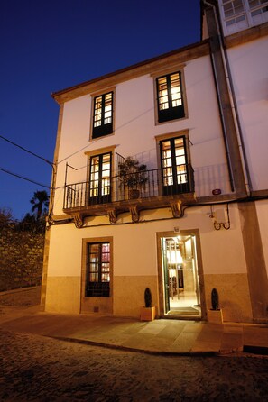 A two-story building with a balcony, a door leading to the interior, and a small garden area with potted plants. - Hotel Altair (Santiago de Compostela)